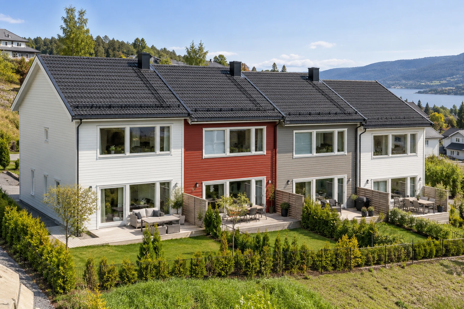 Fire sammenbygde rekkehus med mørke takflater og forskjellige fasadefarger.